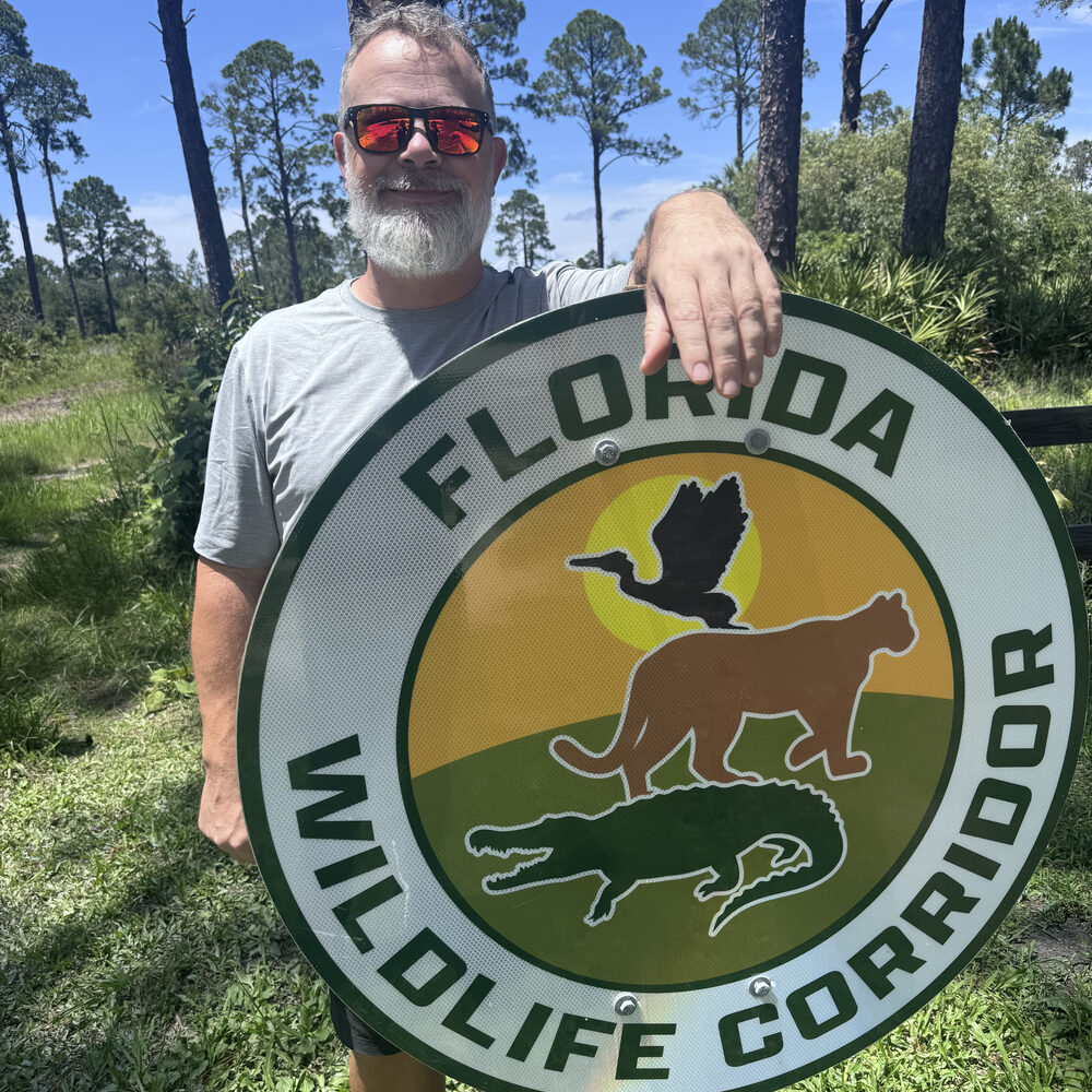 Pete holding a Florida Wildlife Corridor trail marker at Cedar Key Scrub State Reserve